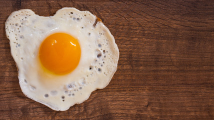 Fried egg on the brown wooden table background. with copy space. top view.