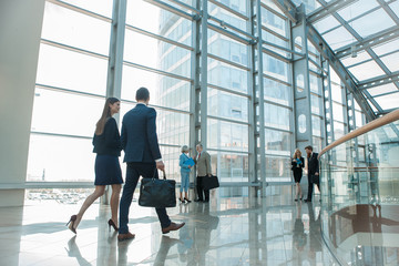 Business people walking in glass building - obrazy, fototapety, plakaty