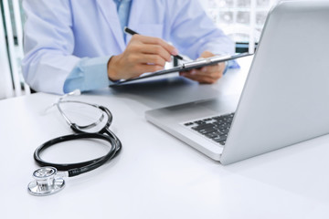 doctor working on laptop with  stethoscope and paper clipboard, selective focus