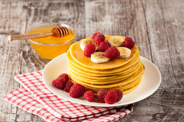Fresh made delicious pancakes with berries, blackberries, raspberries, banana, honey and maple syrup. Healthy morning breakfast concept.