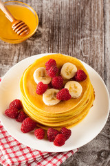 Fresh made delicious pancakes with berries, blackberries, raspberries, banana, honey and maple syrup. Healthy morning breakfast concept.
