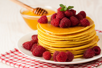 Fresh made delicious pancakes with berries, blackberries, raspberries, banana, honey and maple syrup. Healthy morning breakfast concept.