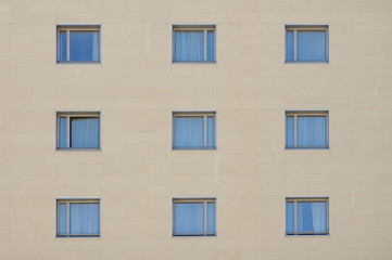 Obraz premium Ventanas cuadradas con cortinas, fachada de un edificio