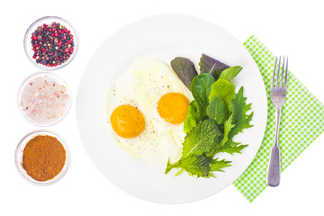 Breakfast.Fried eggs with mix of salad leaves.