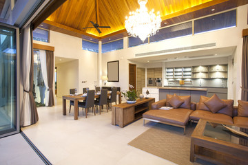 Luxury interior design in livingroom of pool villas. Airy and bright space with high raised ceiling and wooden dining table
