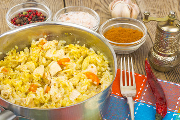 Rice with meat, carrots and spices in metal pan.