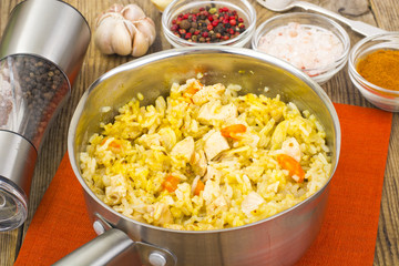 Rice with meat, carrots and spices in metal pan.