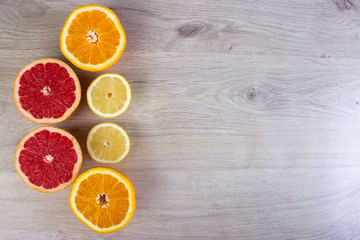 Citrus fruits cut background- oranges, lemons, grapefruit on a bright wooden background