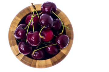 Red ripe juicy cherry in wooden bowl.