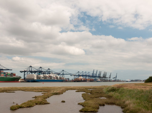 Stock Photo - blue sea structure cranes at cargo dock loading in distance felixstowe essex