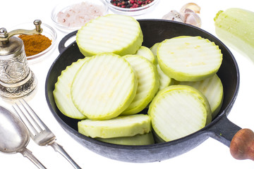 Fresh zucchini, cut into slices, in frying pan on white backgrou