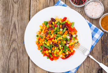 Boiled vegetables in white plate on old wooden table. Healthy ve