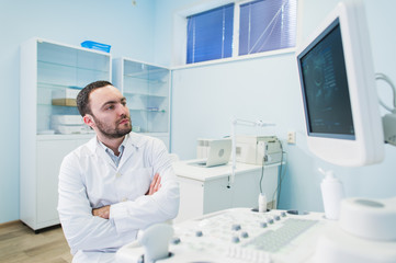 Portrait of a thinking doctor near sceen of medical equipment.