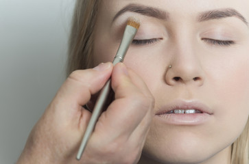 Girl getting eyeshadow powder on eyelids with brush