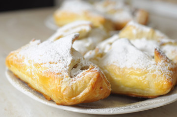 puffs with apple jam and sugar powder on a white plate