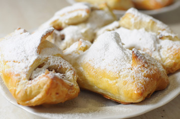 puffs with apple jam and sugar powder on a white plate