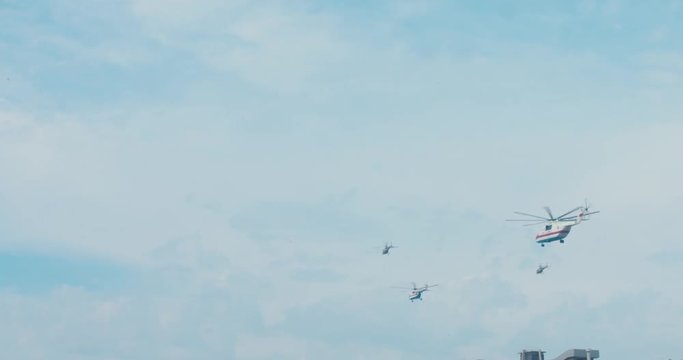 SLO MO WIDE TILT Formation of military fighter helicopters flying towards the horizon against blue sky. 60 FPS 4K UHD 