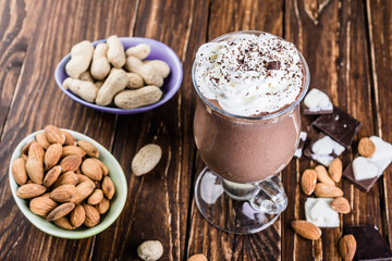 Chocolate banana smoothie with nuts  on a wooden table.