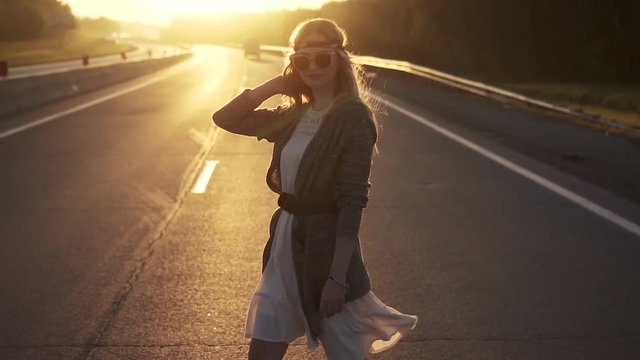 girl dressed in hippie style is on the road. portrait of young woman in sunglasses. slow motion