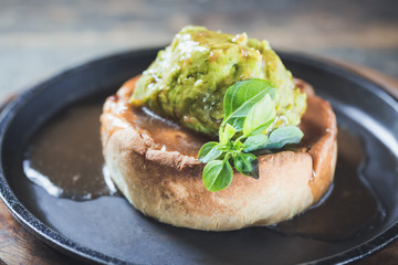 Game pie with duck meat in serving dish with peas puree and spinach leaves close up