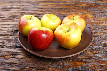 ripe in a dish apples on a wooden table, summer harvest, healthy