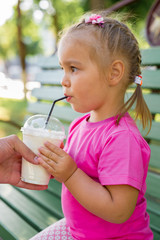 Fototapeta premium Little girl drinking milkshake through a straw