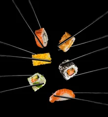 Tuinposter Sushi bar Sushi stukken geplaatst tussen eetstokjes, op zwarte achtergrond
