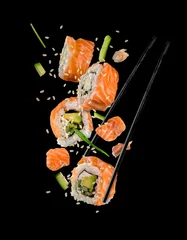 Foto op Plexiglas Sushi pieces placed between chopsticks on black background © Jag_cz