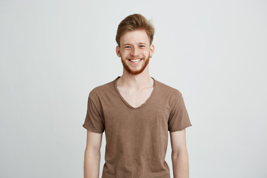 Portrait of happy cheerful young man with beard smiling looking at camera over white background.