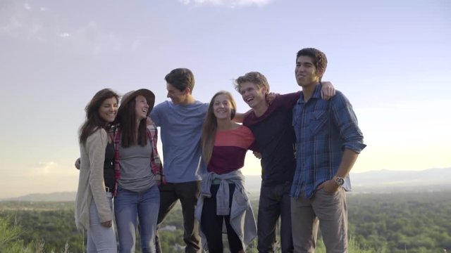 Group Of Teens Hold Each Other And Smile, Then Jump In The Air (Slow Motion)