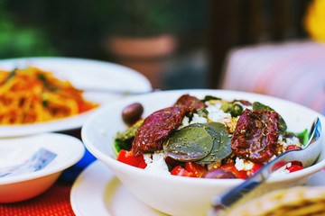 Healthy vegan food - closeup of salad with sundried tomatoes, capers leaves.