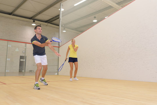 couple playing in indoor tennis court