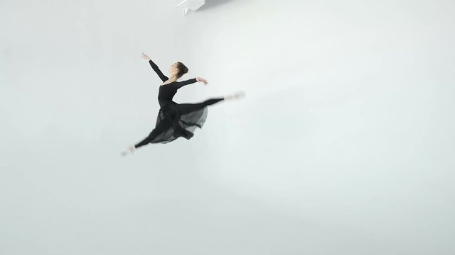 Shapely 20s dancer girl in black beautifully dances in front of a large window in white ballroom 20s 1080p slow motion