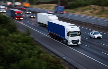 Lorries in motion on the motorway at the dusk time