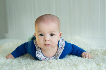 A little European-looking girl with big brown eyes lying on her belly with a keen eye