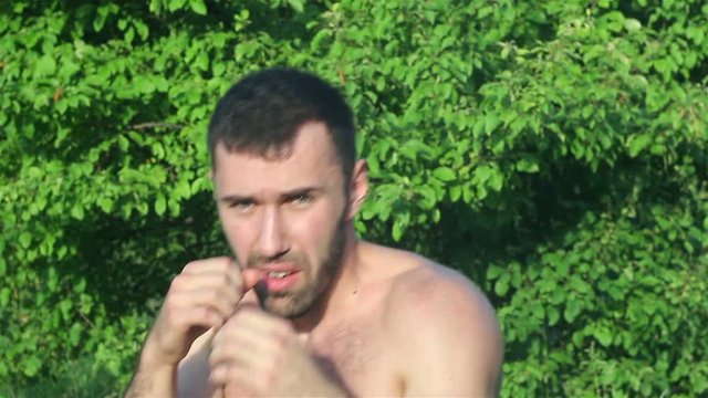 Kickboxer trains blows in front of a big battle. in the park
