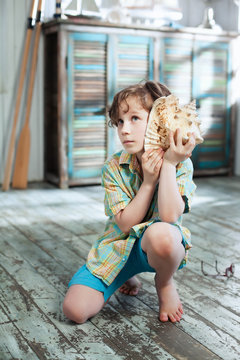 A boy listening to the sound of the sea in a large shell