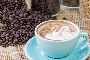 Cup of coffee on coffee beans background on a wooden table