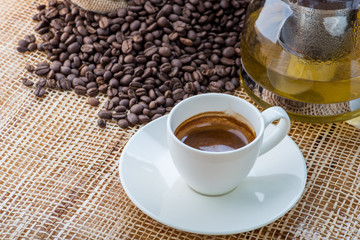 Cup of coffee on coffee beans background on a wooden table