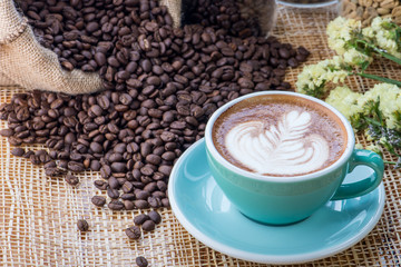 Cup of coffee on coffee beans background on a wooden table