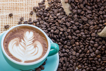 Cup of coffee on coffee beans background on a wooden table