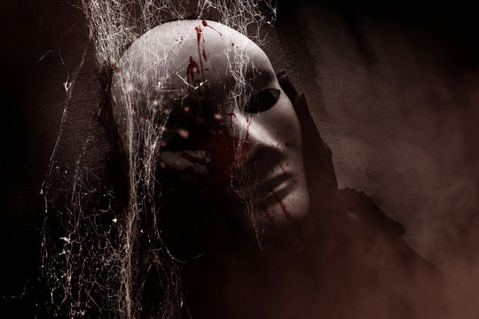 Mysterious woman in black wearing white mask hidden behind spider web,Scary background for book cover