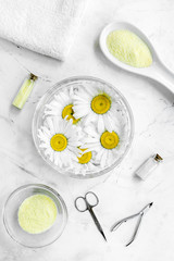 Manicure set with spa salt, chamomile and towel on white desk top view