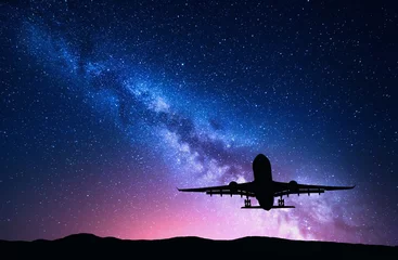 Fotobehang Milky Way and silhouette of a airplane. Landscape with passenger airplane is flying in the starry sky at night. Space background. Landing airliner on the background of colorful Milky Way. Aircraft © den-belitsky
