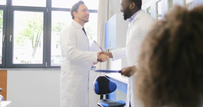 Two Male Scientists Handshake In Laboratory Congradulating With Successful Experiment Results Over Busy Team Of Scientific Workers Slow Motion 60
