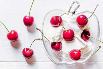 Obraz na płótnie Canvas Ice cream decorated with fresh cherry on white table background top view