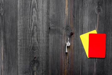 Yellow and red referee cards and whistle on wooden background top view copyspace