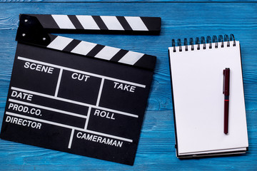 Work table of producer. Movie clapperboard and notebook on blue wooden table background top view