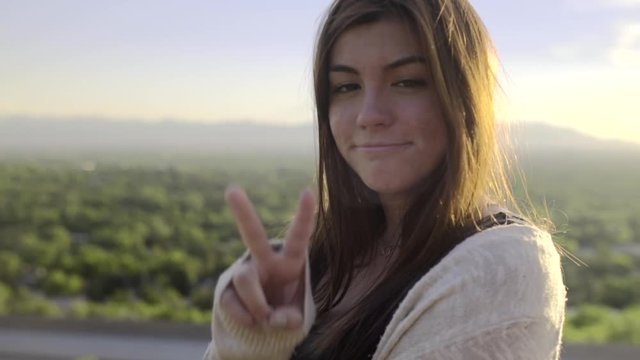 Teenage Girl On A Road Trip,Smiles And Gives Peace Sign, At Scenic Overlook (Slow Motion)