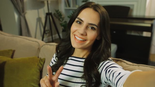 Attractive woman video chatting, skyping with family, friends. Woman waving at the camera and smiling. close up